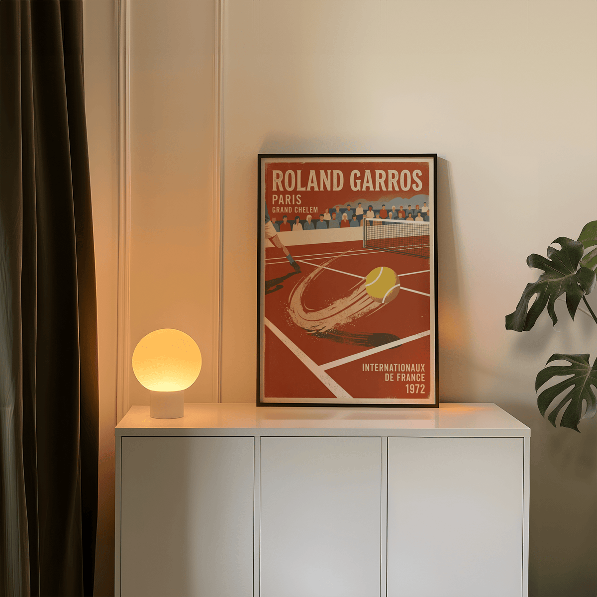 Print leaning on a shelf showing a vintage tennis ball on clay court with an orange lamp nearby