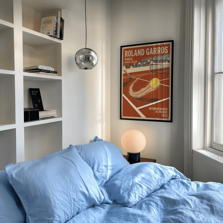 Print on a wall in a bedroom featuring a tennis ball on a clay court with vintage style and blue bedding