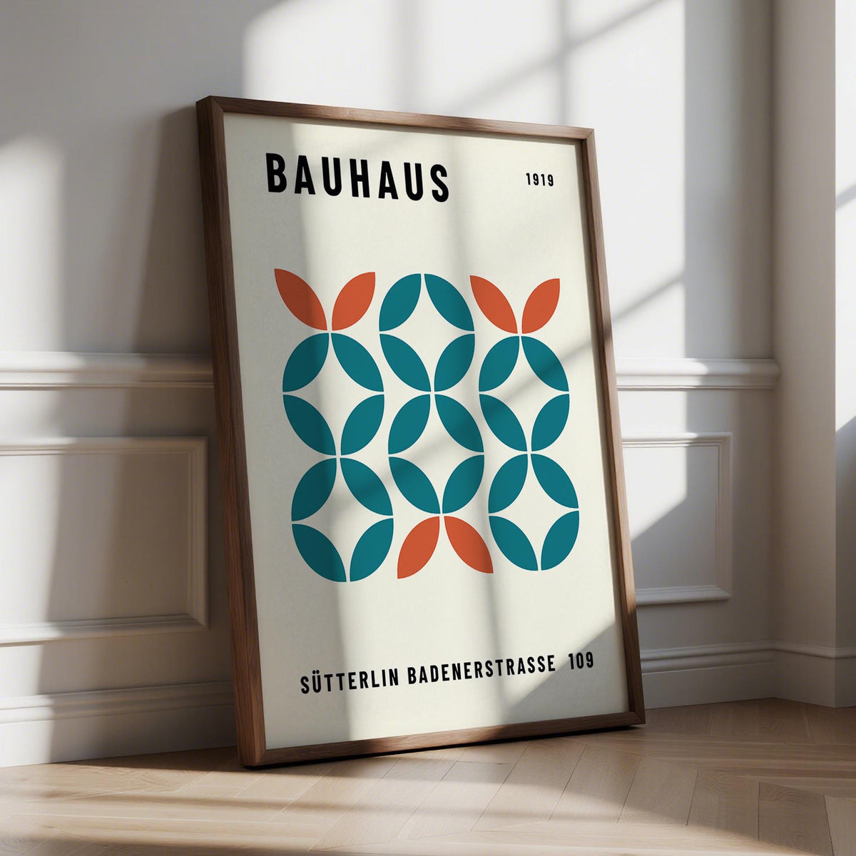 Print leaning on a floor showing geometric pattern with blue and orange shapes and black text
