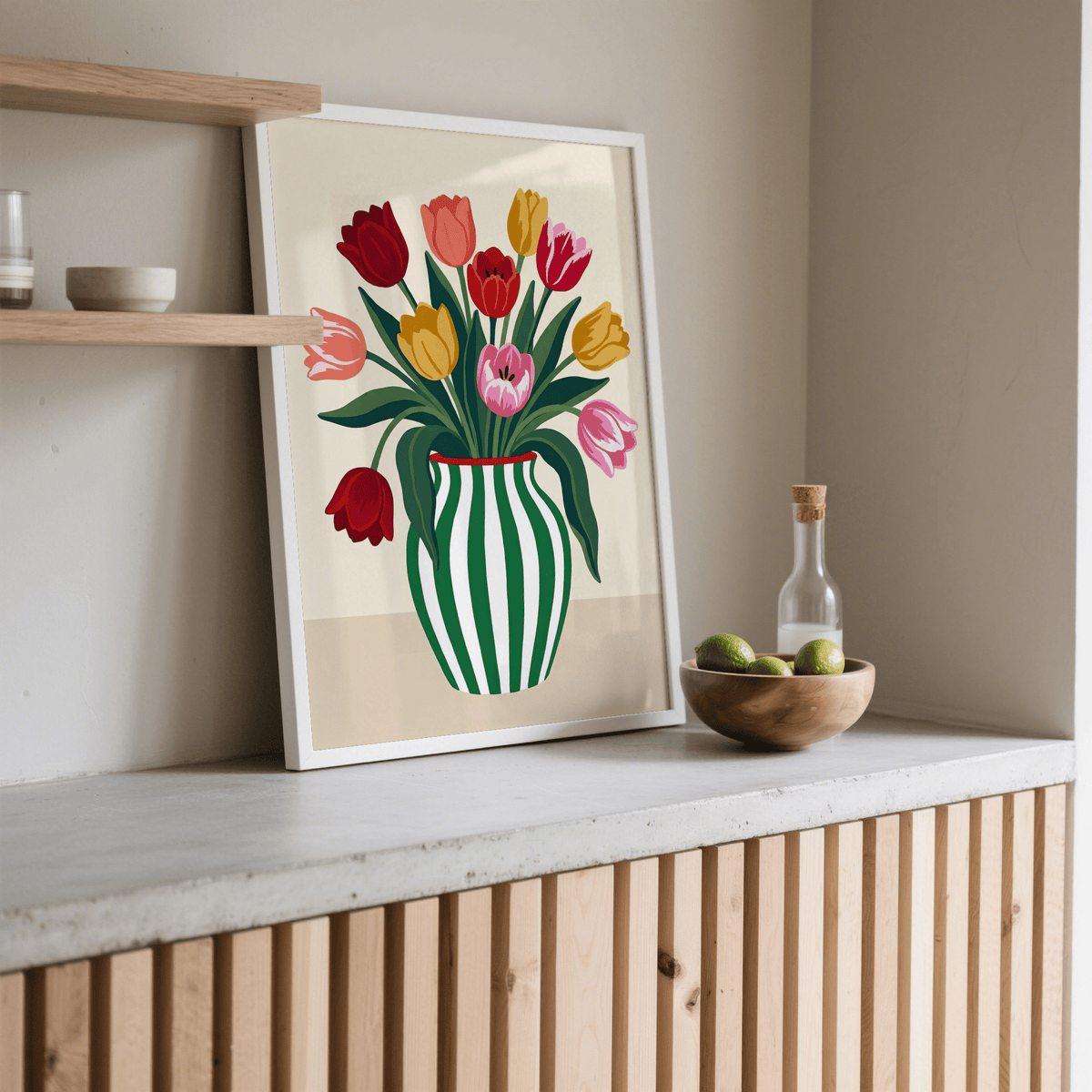 Print leaning on a shelf of tulip art print with multicolour tulips and striped vase next to a bowl of fruit