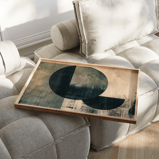 Contemporary Poster Art leaning on a beige cushion with large dark circle and half circle shapes