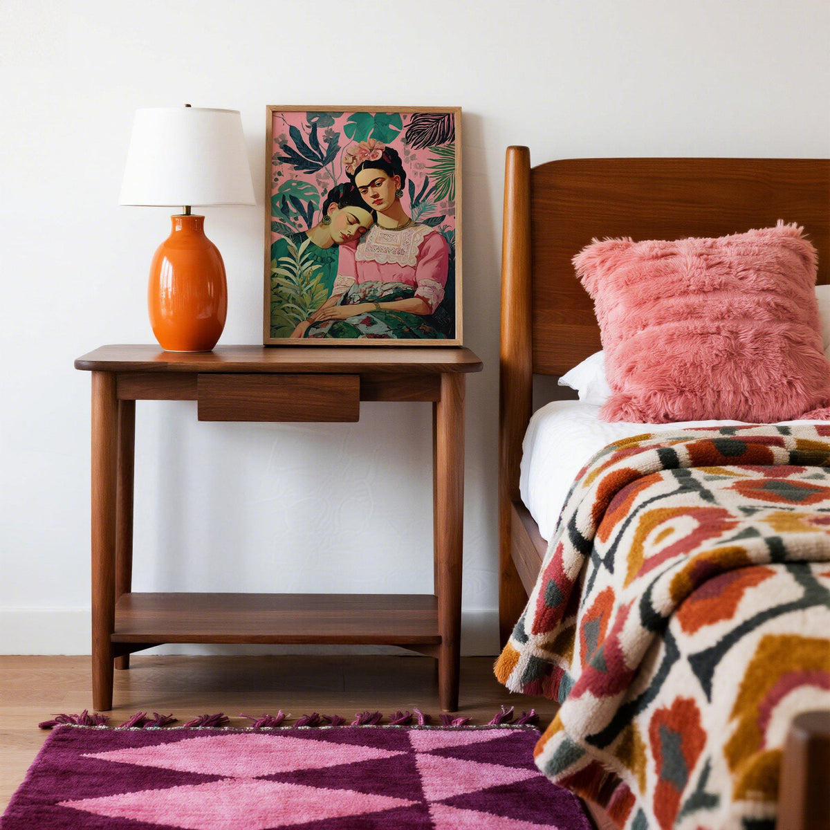 Frida Kahlo wall art portrait of two women with pink and green tones on a bedside table next to an orange lamp
