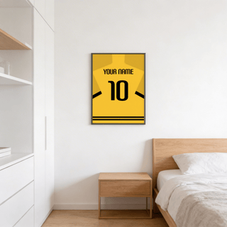 Football Shirt Poster in Yellow with Black Sleeve Stripes in a bedroom above a wooden bedside table