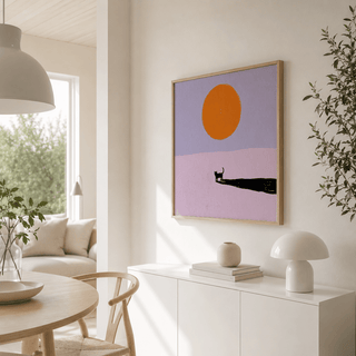 Minimalist Cat Art Print framed print on a wall showing a black cat silhouette and orange sun with soft purple background in a dining area