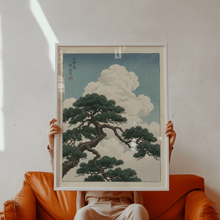 Japanese Landscape Poster framed print close-up featuring pine tree branch with blue sky and clouds held on an orange sofa