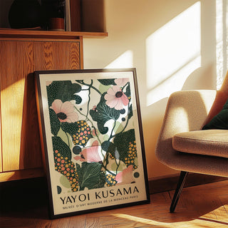 Print leaning on floor of wall art with pink flowers and dark green leaves near wooden cabinet and sofa