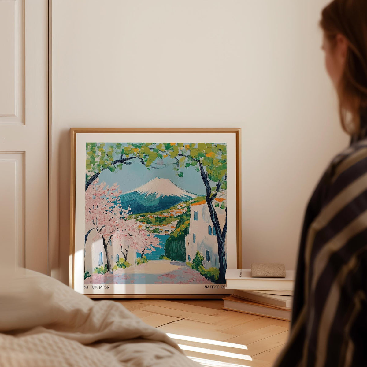 Print leaning on the floor of Mount Fuji with cherry blossoms in spring colors beside a stack of books