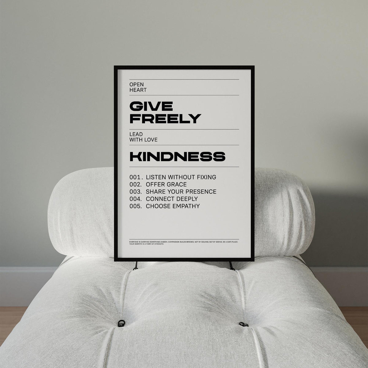 Art with Quotes print with 'Give Freely Kindness' text in black on white leaning on a white cushioned chair