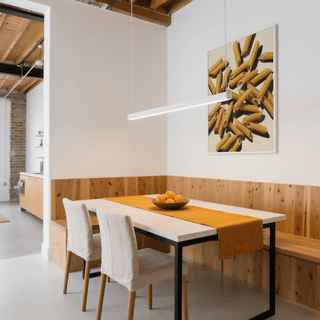 Penne Art wall art showing illustrated penne pasta in yellow and cream above a wooden dining table with orange runner and fruit bowl