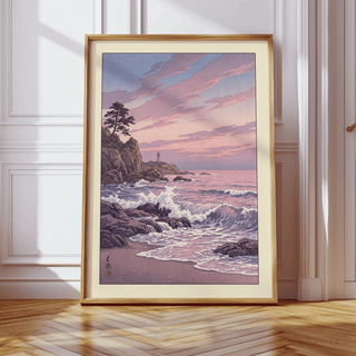 Print leaning on a wooden floor of rocky coastline at sunset with pink and purple tones near white wall