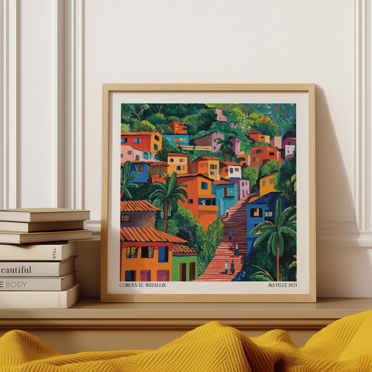 Framed Comuna 13 Art print of colourful hillside houses with green trees on a wooden shelf near stacked books