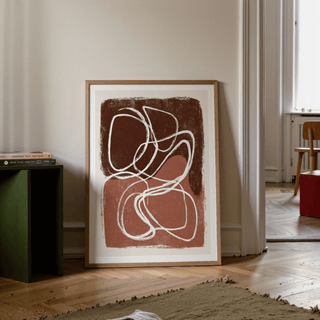 Print leaning on floor minimalist shapes wall art with brown and terracotta colours near green side table