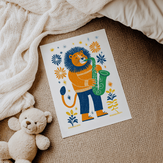 Saxophone Lion Art Print laid on a carpet next to a teddy bear with neutral-toned blanket