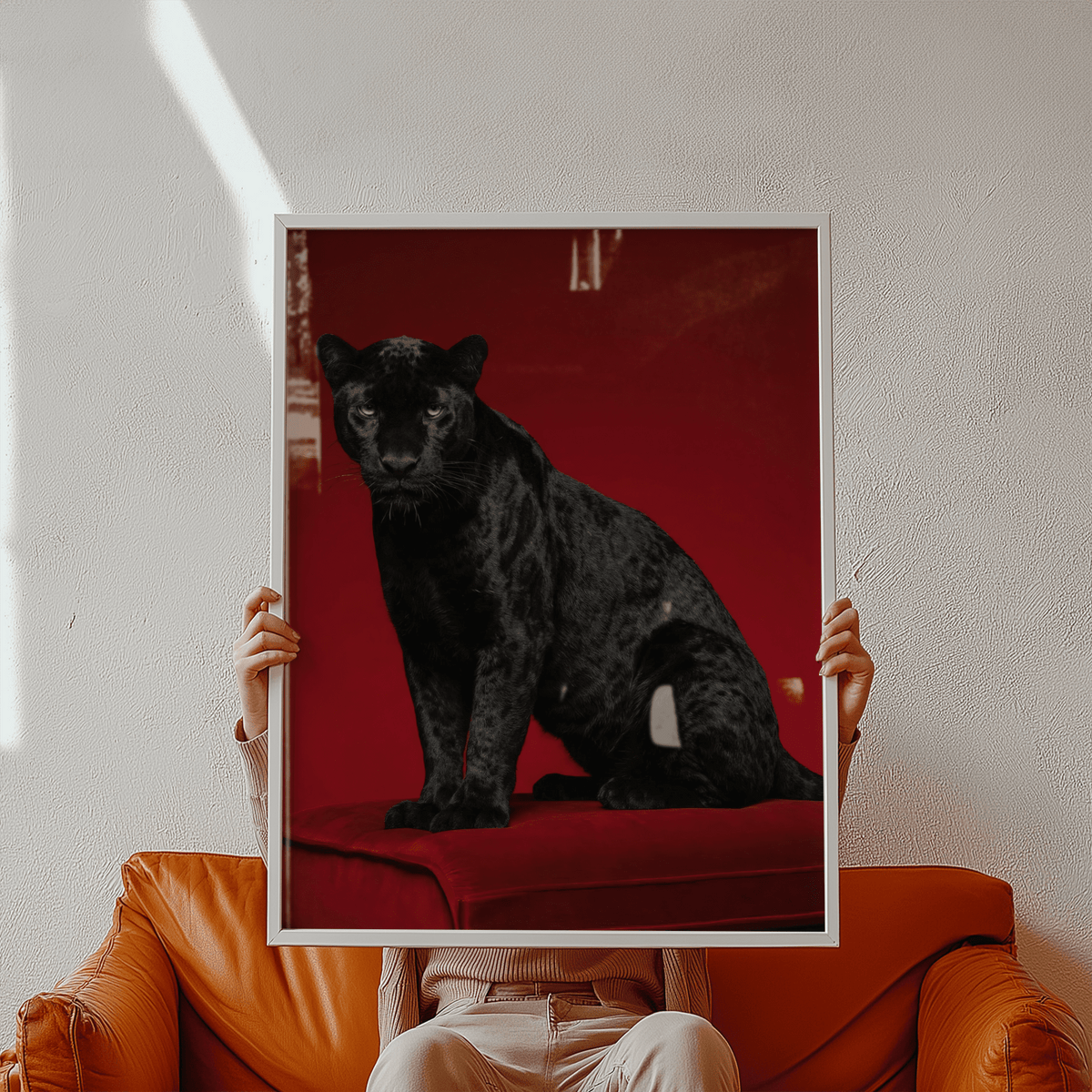 Framed Black Panther Art Print held by person wearing beige on a brown leather sofa