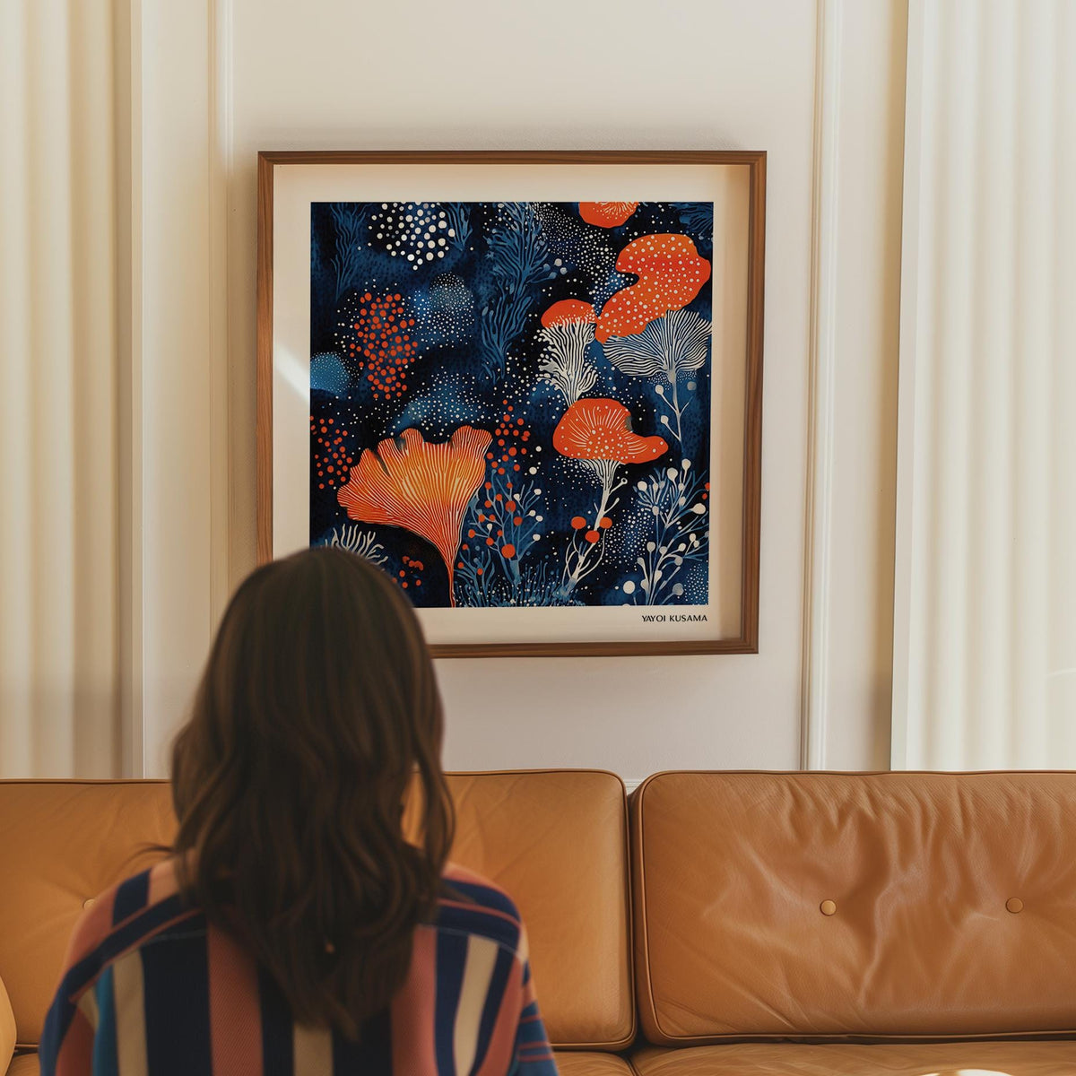 Unique living room wall art showing abstract floral shapes in blue and orange above a tan leather sofa