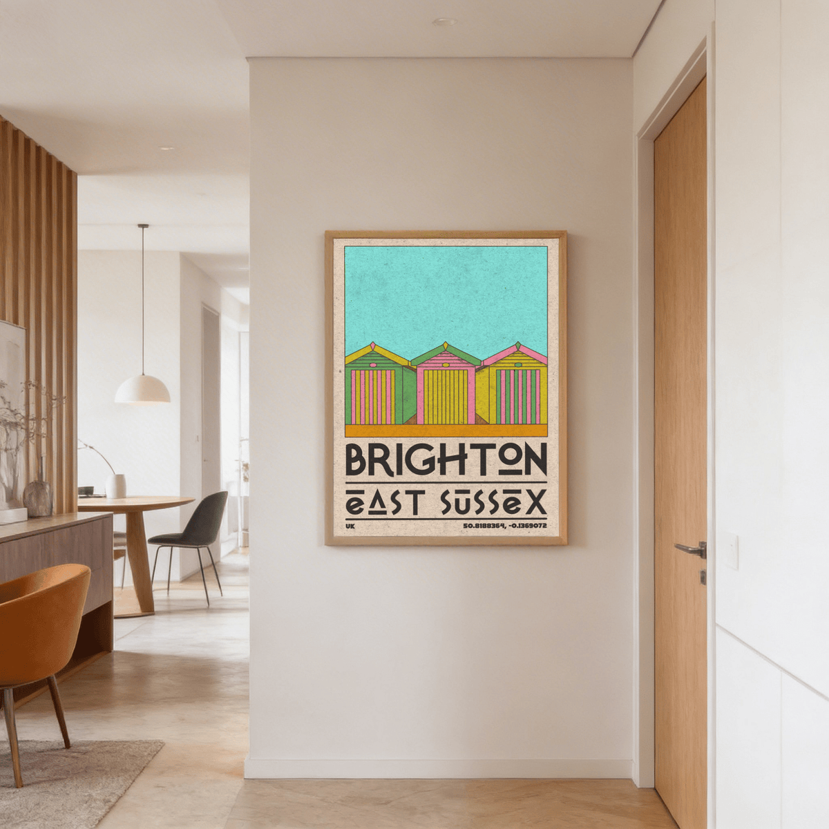 Brighton Travel Print hanging on a hallway wall showing colorful retro beach huts in blue yellow and pink
