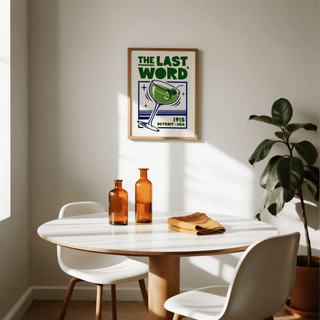 Cocktail Art Print framed on wall above a round table with amber bottles and white chairs in a dining room