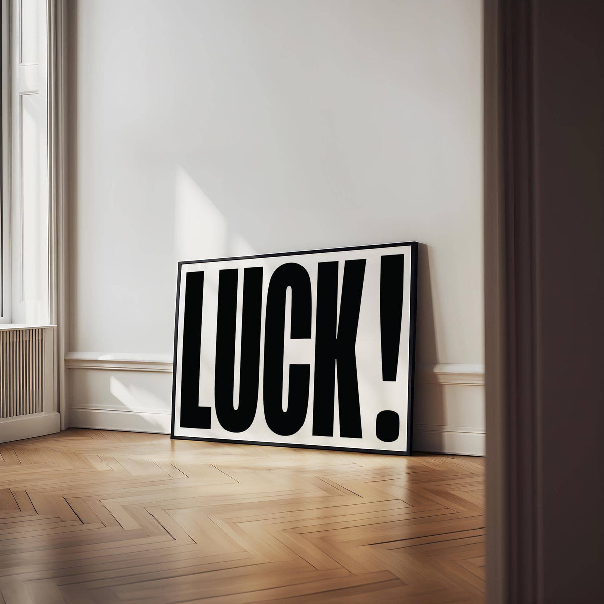 Good Luck Print leaning on a wooden floor against a white wall with sunlight streaming in