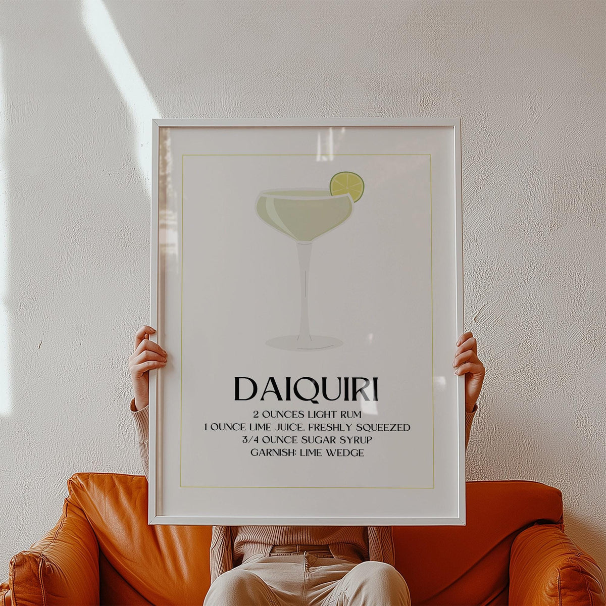Framed Kitchen Pictures Decor with daiquiri cocktail illustration and recipe held by person on an orange chair