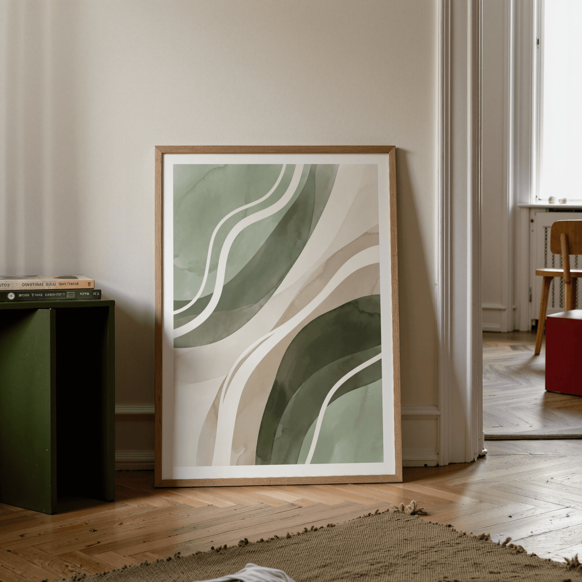 Print leaning on floor with green abstract shapes beside a green table and books