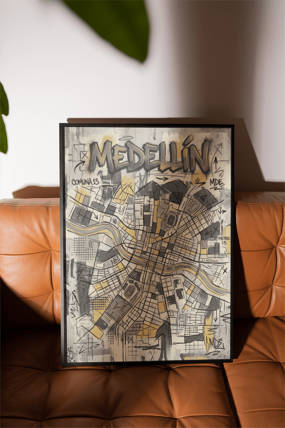Framed Medellin Map Art Print leaning on orange leather sofa with abstract map details
