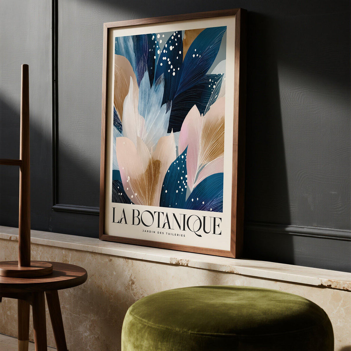 La Botanique print leaning against a dark grey wall with green velvet stool and wooden table leg