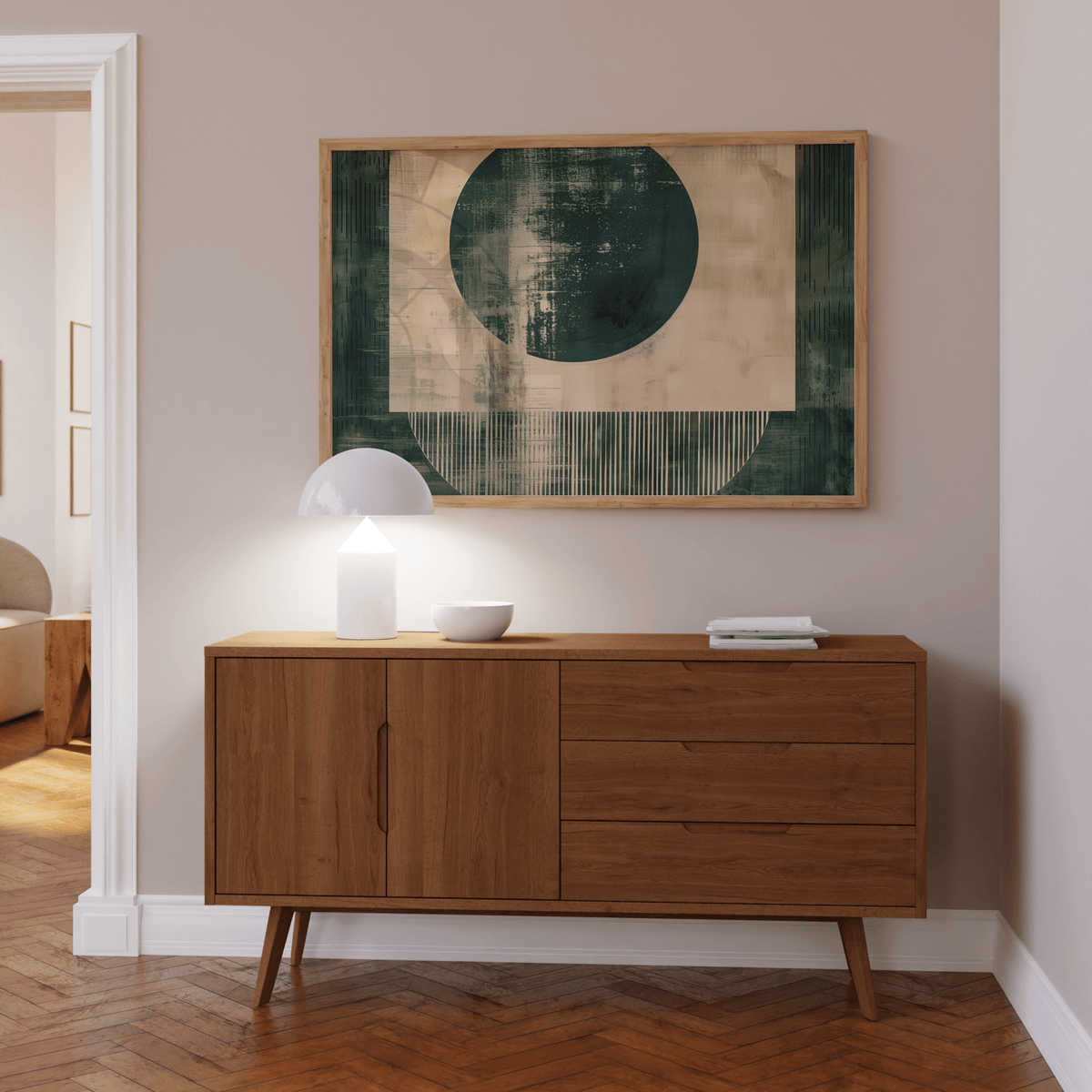 Abstract geometric poster with green and beige shapes above a wooden sideboard with a white lamp
