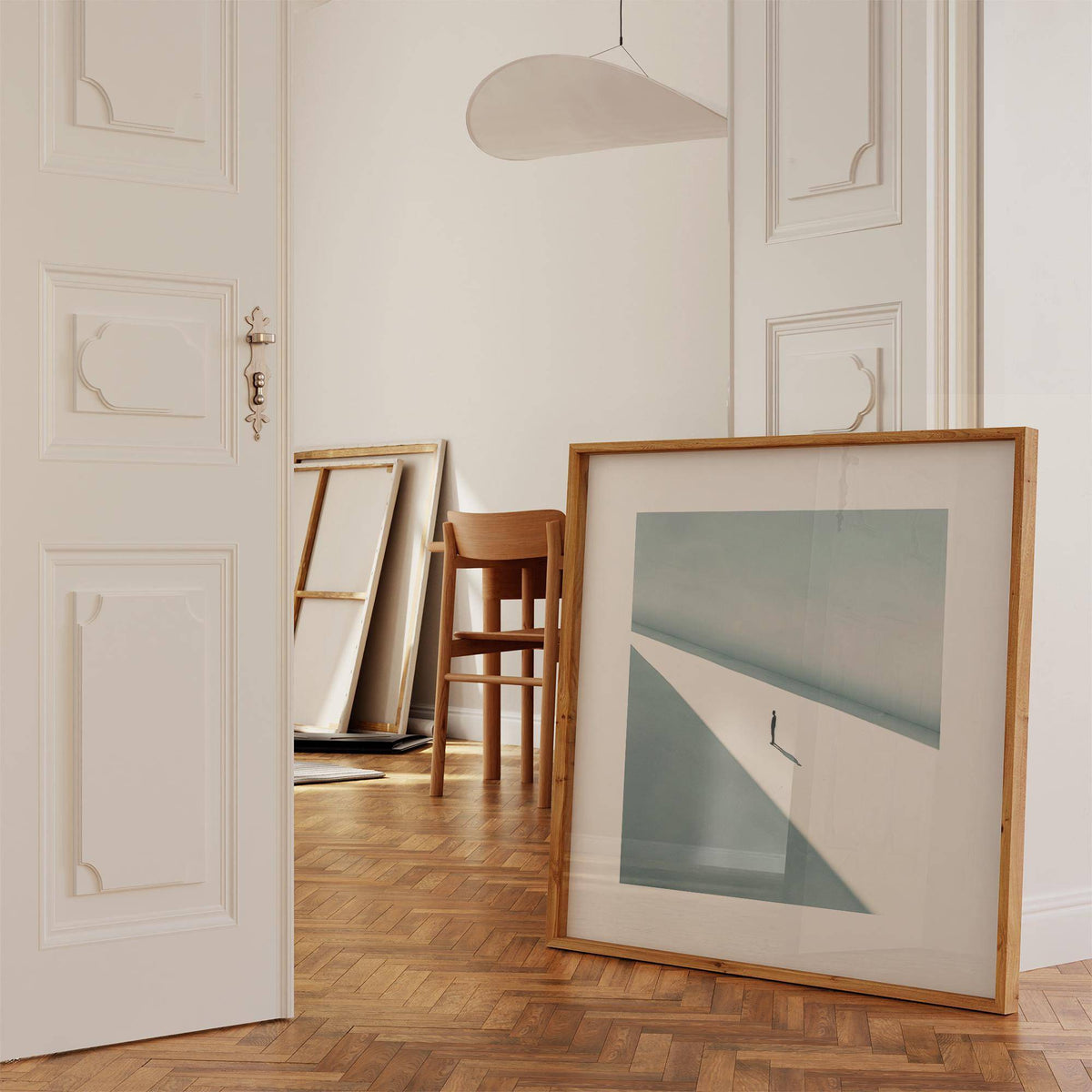 Art Prints Square print leaning on floor showing a solitary person in shadow with muted blue and white tones in an airy room wooden chair