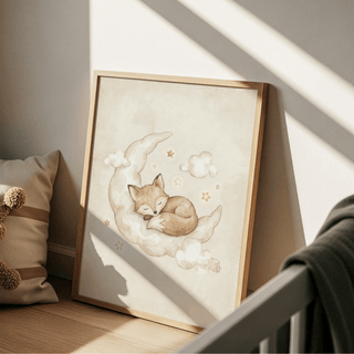 Print leaning on a floor with a sleeping fox on a crescent moon in soft brown and cream colours near a pillow