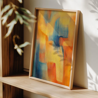 Modern Art Posters framed print with abstract orange yellow and blue shapes leaning on a wooden shelf with plant shadow