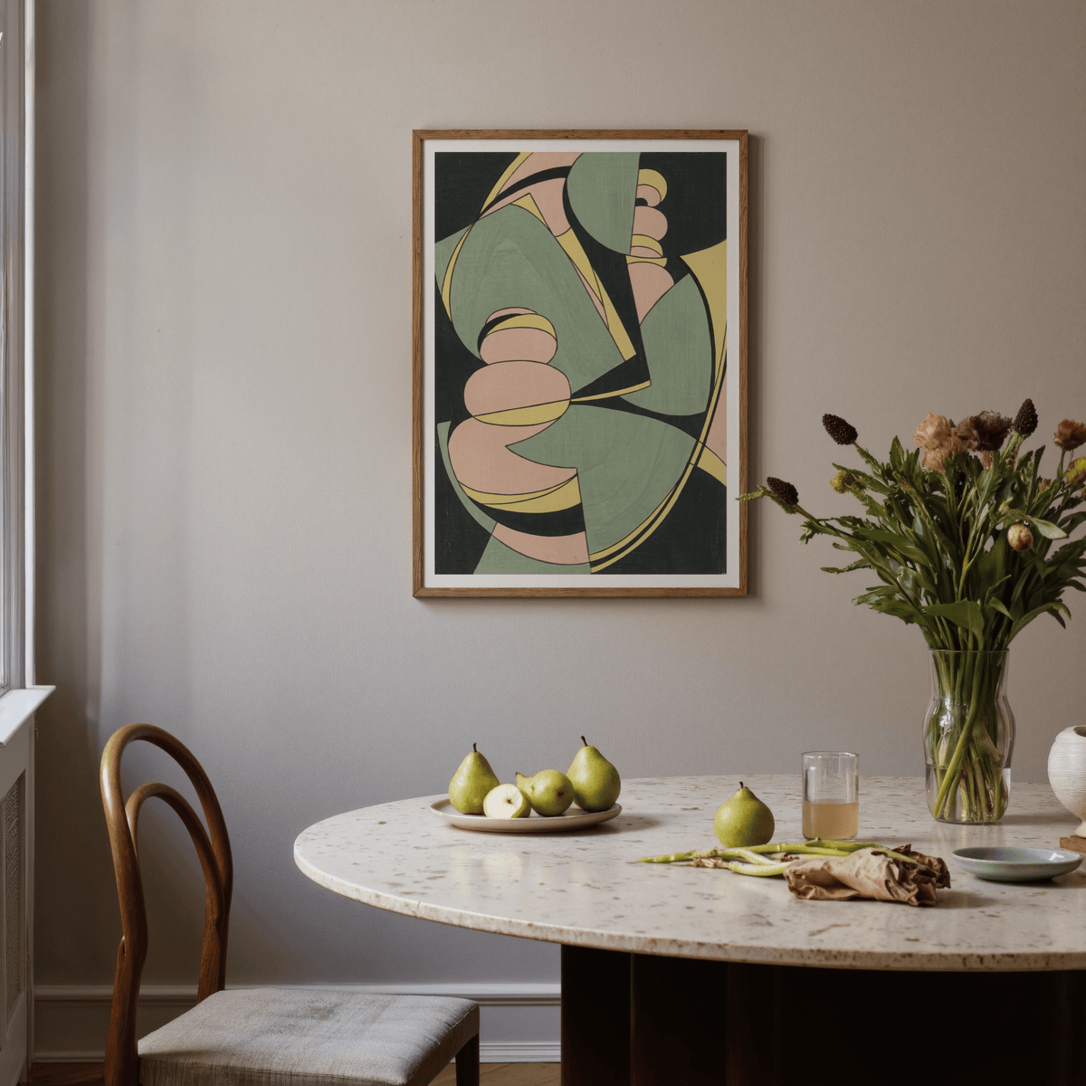 Abstract Geometric Art print in green, pink and yellow hanging above a dining table with pears