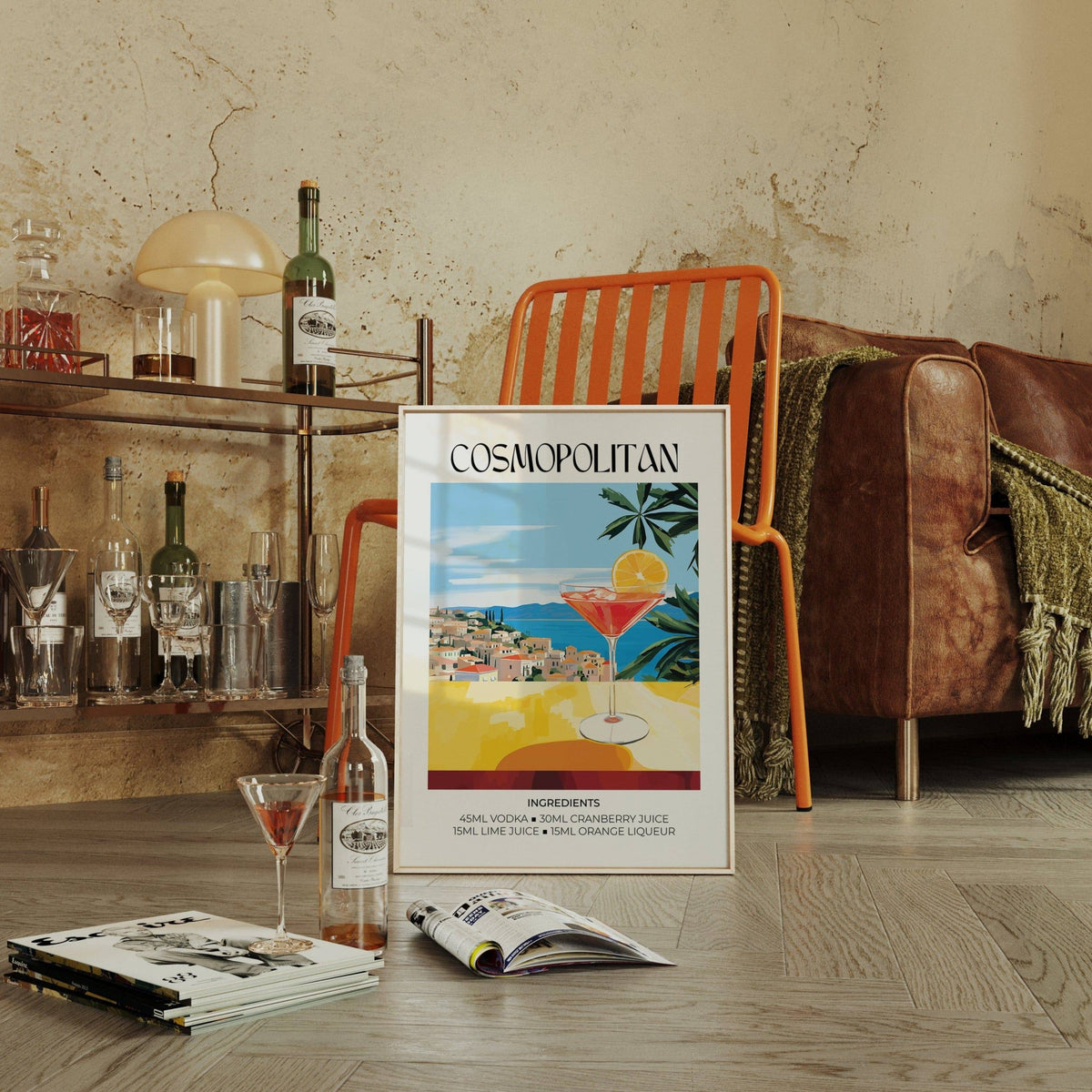 Print leaning on a wooden floor showing a cosmopolitan cocktail glass with bright colours and a vintage style with an orange chair nearby