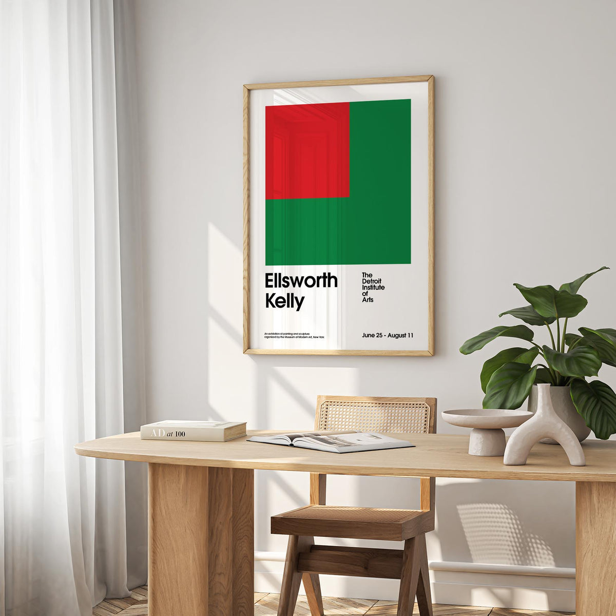 Office Poster print with red and green geometric shapes above a wooden desk with books and a plant