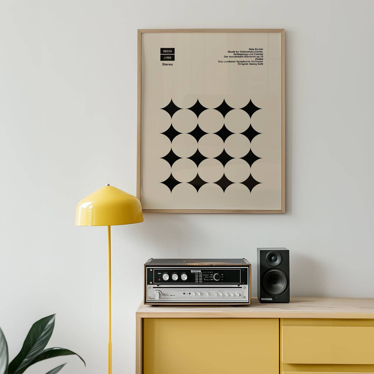 Graphic Art Poster framed print with black star shapes in a minimalist style above a yellow sideboard with a lamp and speaker