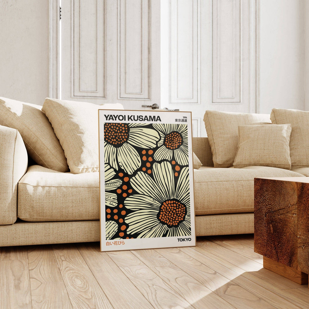 Modern Floral Art Print leaning on the floor with beige daisies and orange centres near a beige sofa