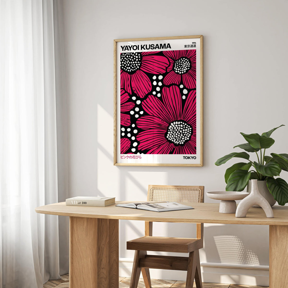 Pink Posters print of red daisies in pop-art style above a wooden desk with books and ceramic object
