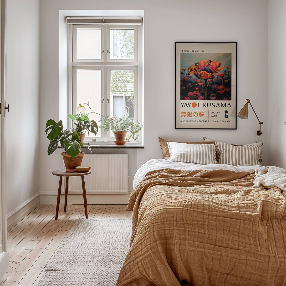 Colourful flower prints framed on a bedroom wall above a beige bed with striped cushions