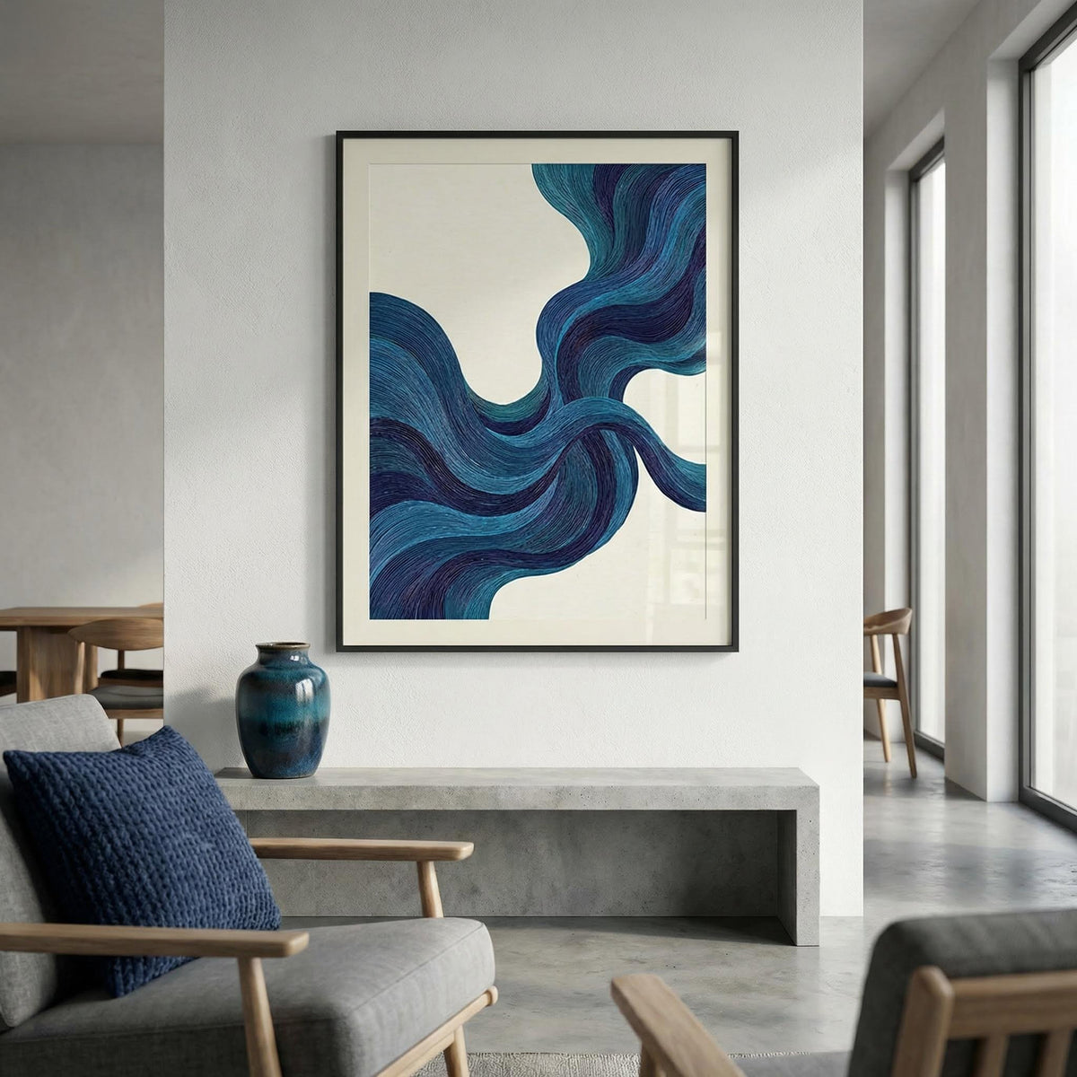 Blue line wall art with flowing blue lines in black frame above a concrete bench with a blue vase in a living room