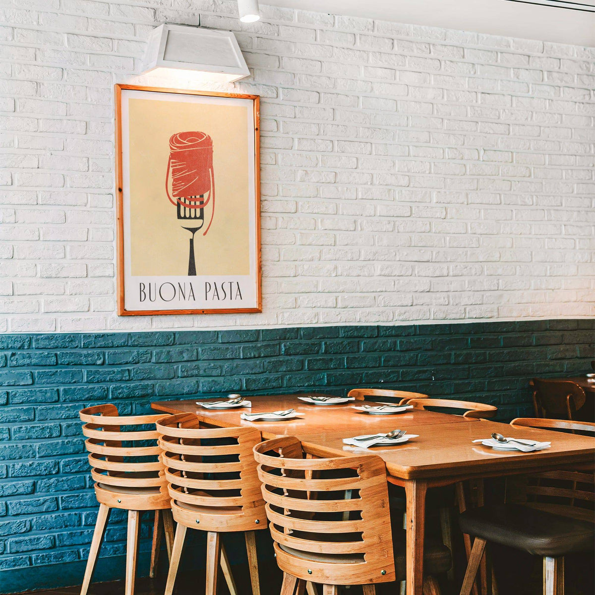 Pasta wall art above a dining table in a restaurant with wooden chairs and brick walls