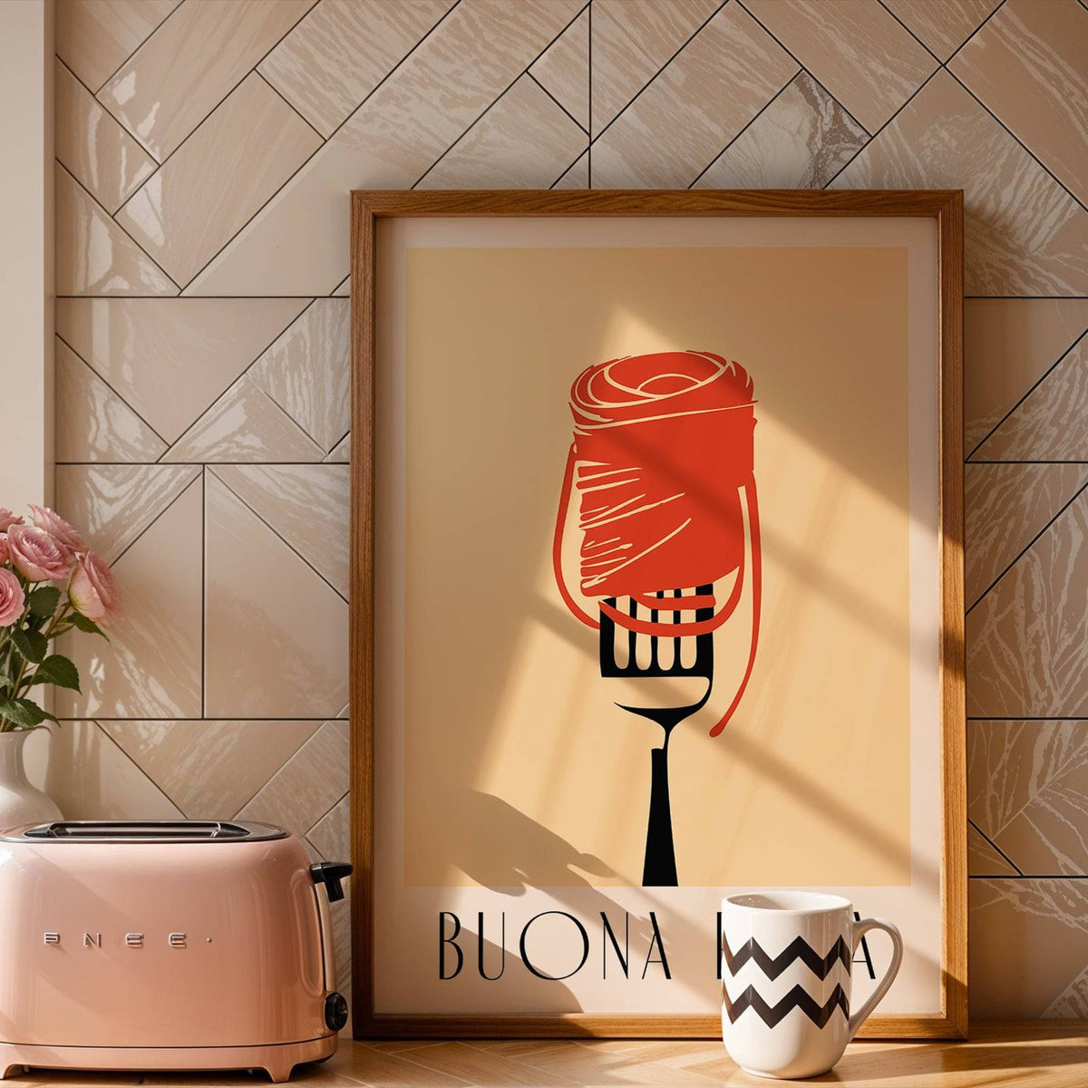 Framed Pasta Wall Art with minimalist red pasta on fork and text leaning on a kitchen surface near a mug
