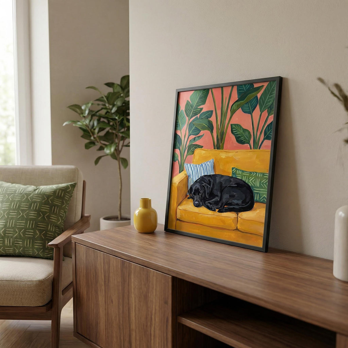Print leaning on a sideboard of a black labrador on a mustard sofa with green cushions near a yellow vase