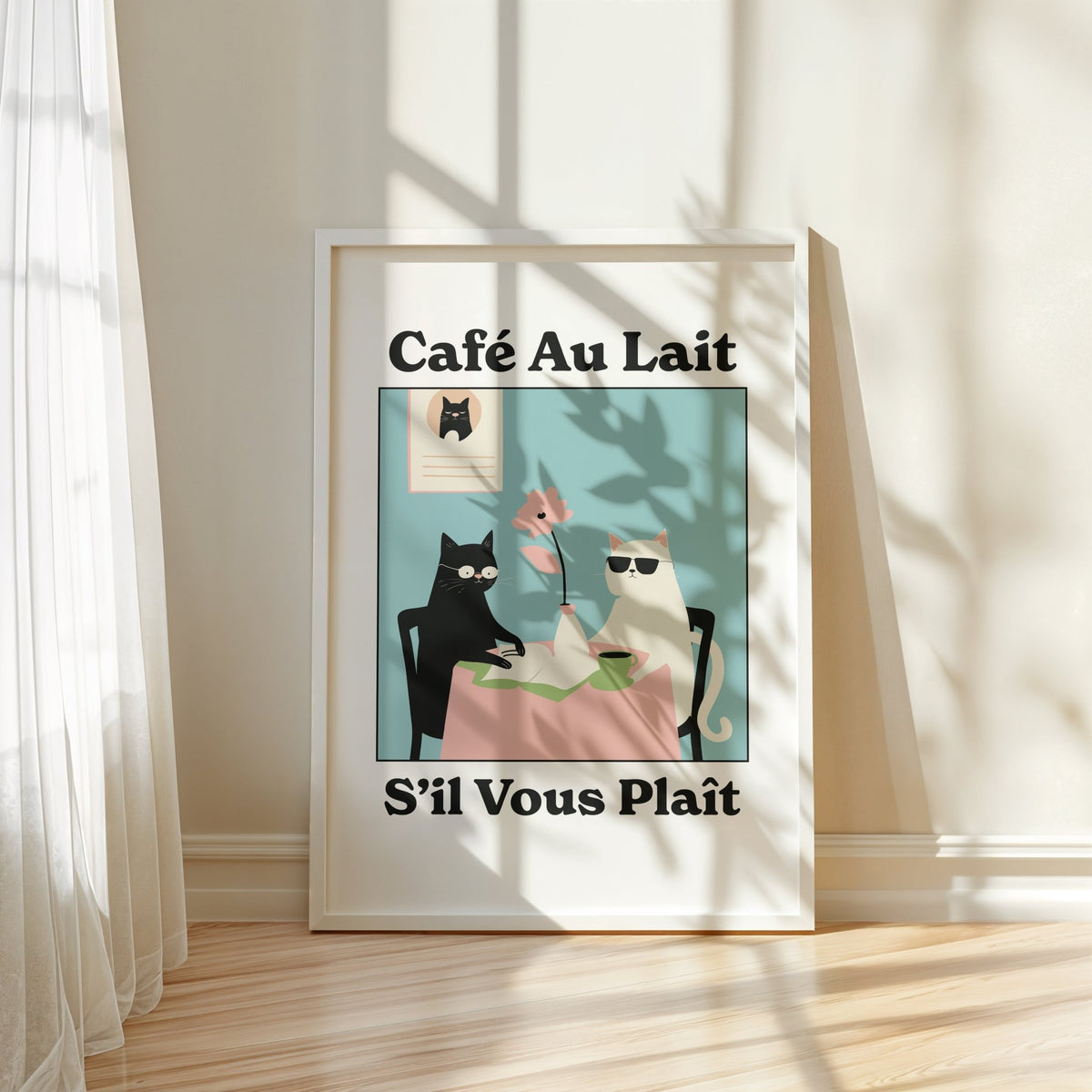 Framed print of quirky kitchen wall art showing black and white cats at a table with a pink cloth leaning on a floor by a window
