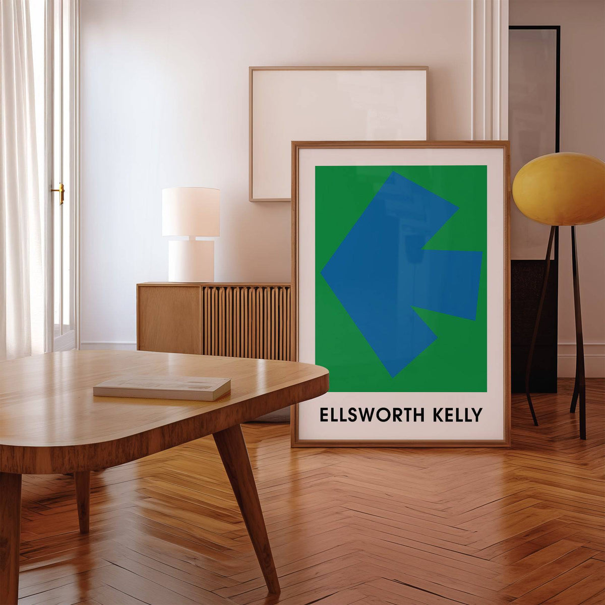 Ellsworth Kelly Art Print leaning on wooden floor beside a yellow floor lamp and wooden table