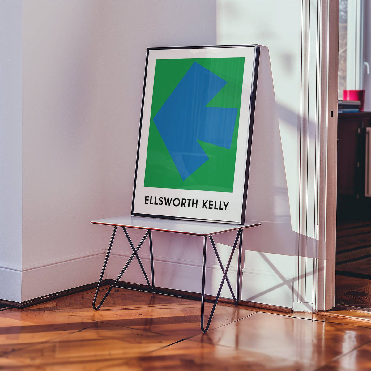 Print leaning on a table of Ellsworth Kelly art print with a blue arrow on green background and black frame