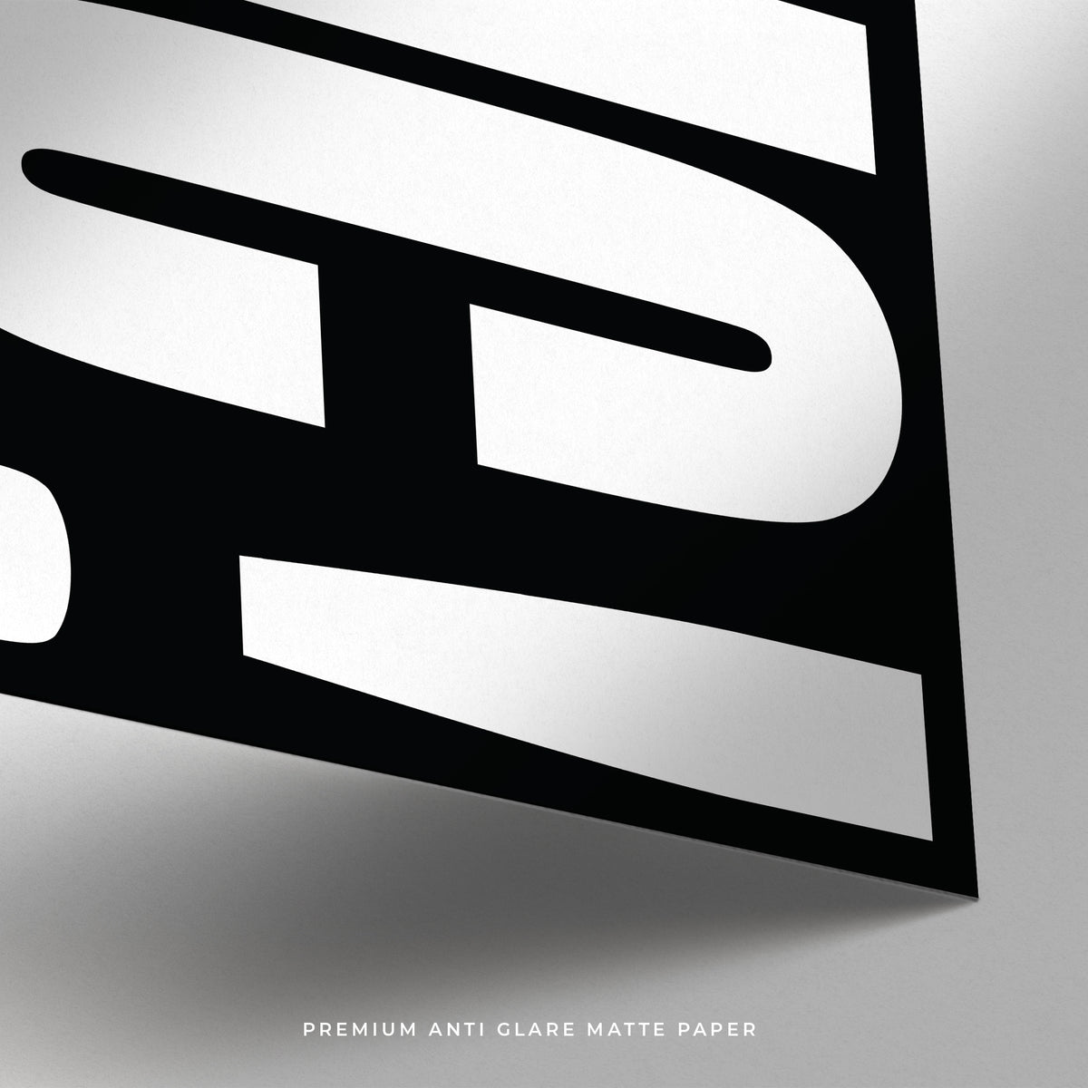 Detail close-up of bold white typography on black matte paper showing curved letter parts