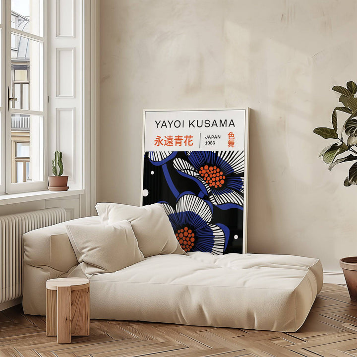 Blue Flower Poster print leaning on a wall with blue and white graphic flowers beside a large cream sofa and wooden side table