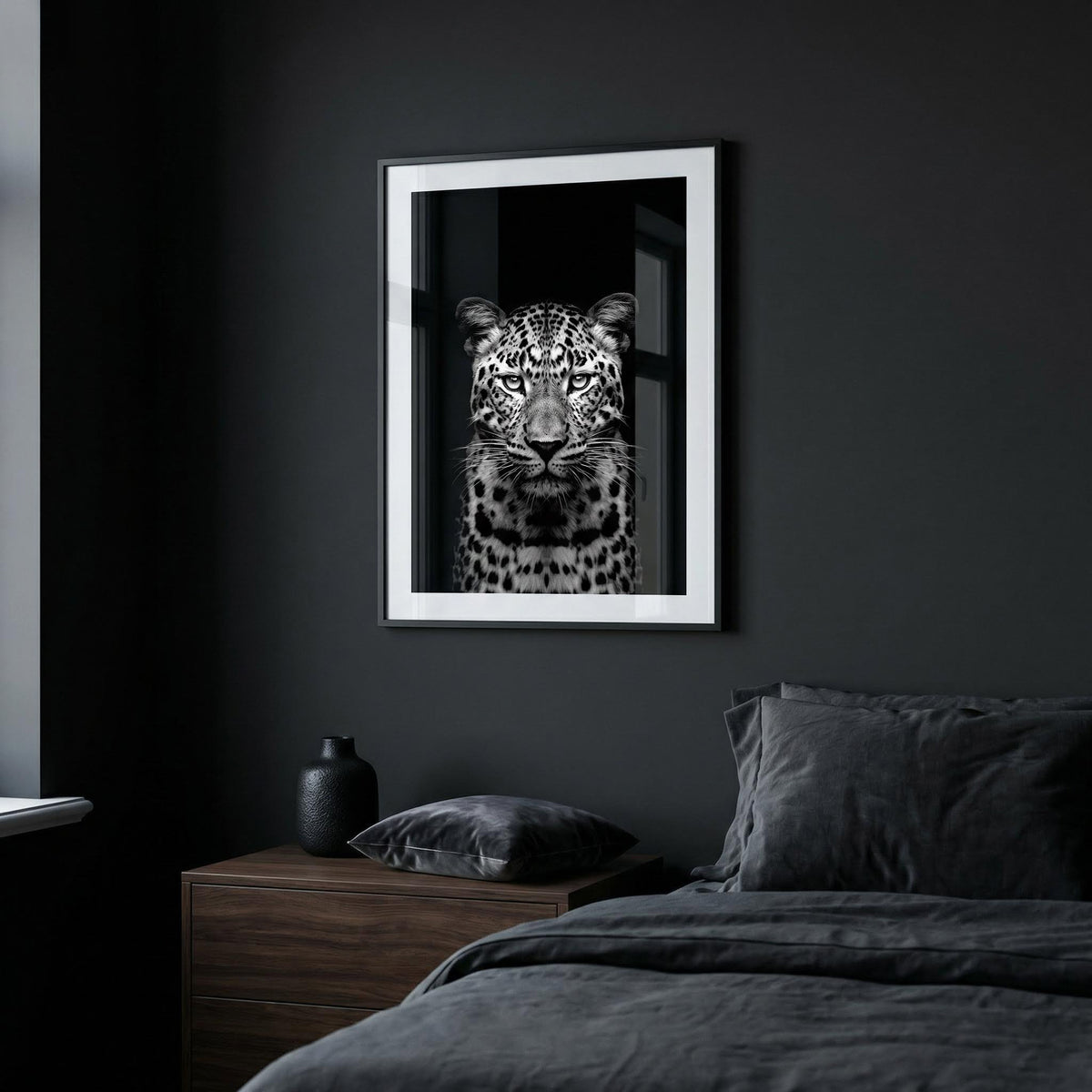 Black Leopard Art Print in a bedroom with dark walls above a wooden bedside table with a black vase