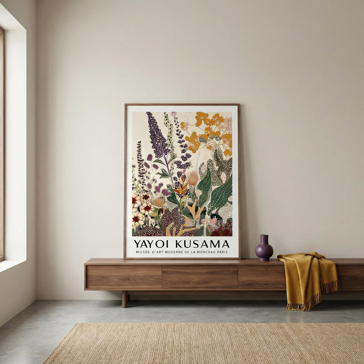 Framed Yayoi Kusama artwork on a wall above a wooden console table.