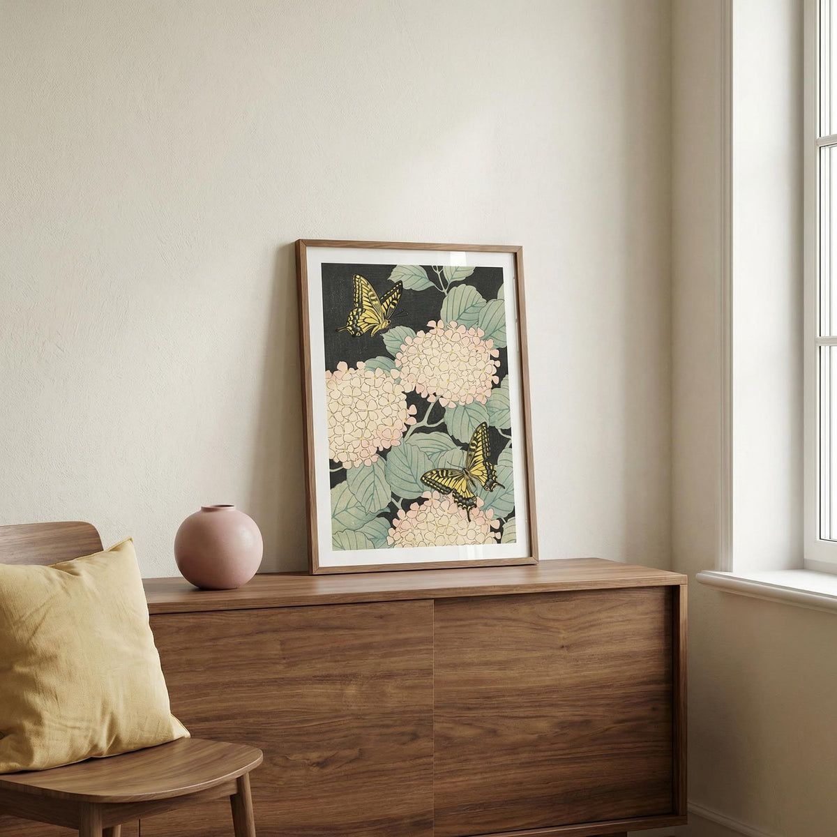 Butterfly art print leaning on a wooden sideboard with pink flowers and yellow butterflies beside a pink vase
