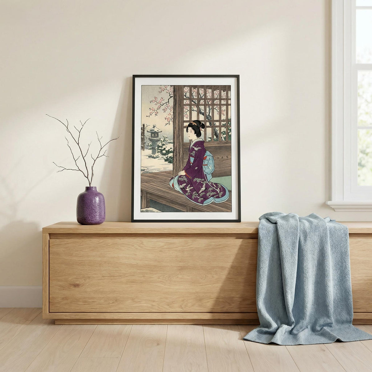 Print leaning on a wooden cabinet of Hasui Kawase Geisha Print with a purple kimono and cherry blossoms near a window